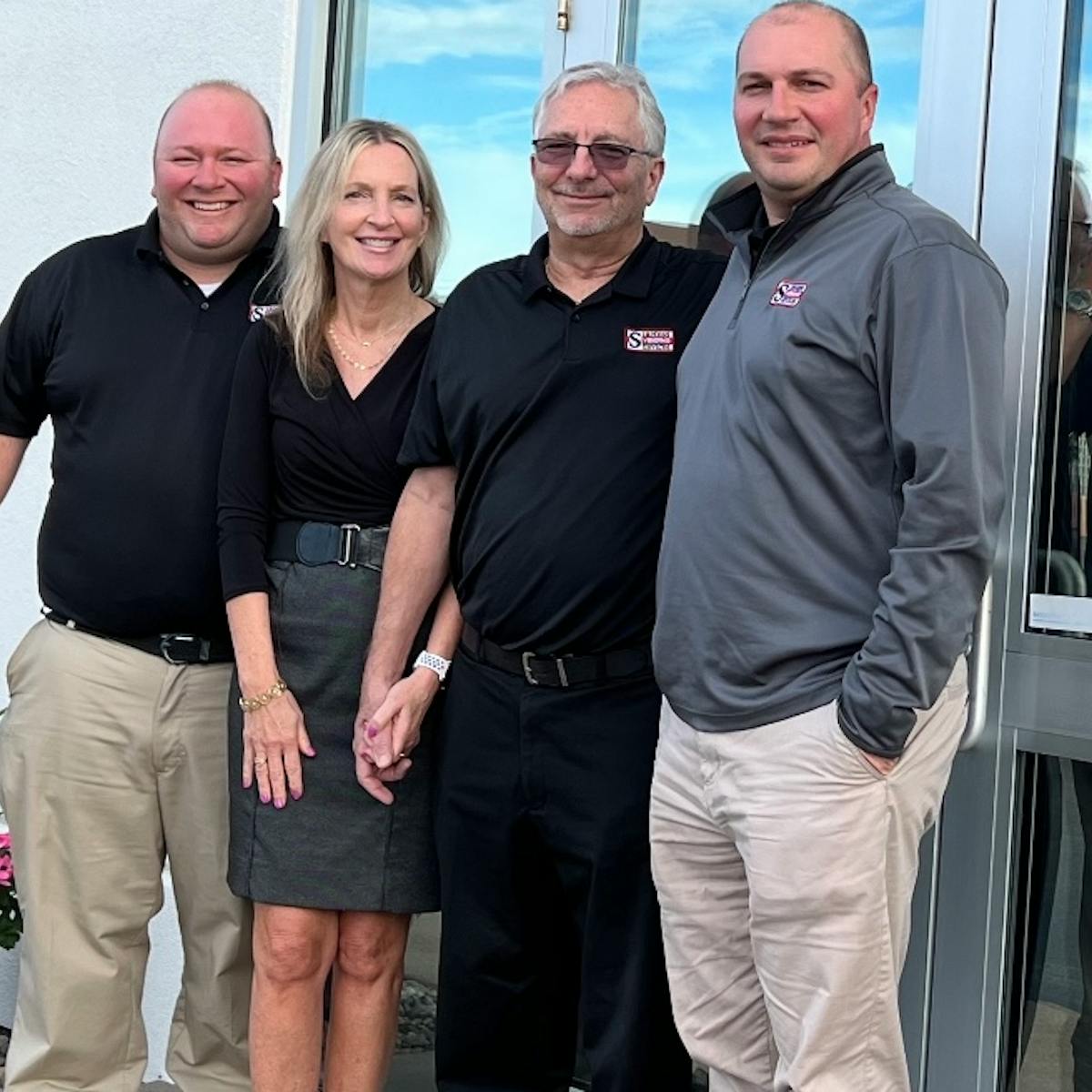 Larry Bach, Barbie Nesser, Tom Nesser and Tom Bach at the main entrance of their Rochester, New York, headquarters.